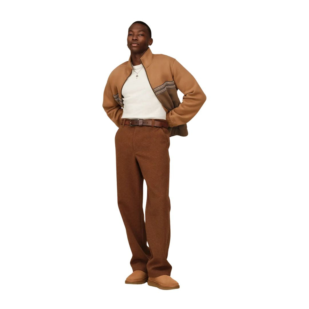 Modelo vistiendo botas UGG Neumel Chelsea color castaño combinadas con pantalón marrón y chaqueta camel.