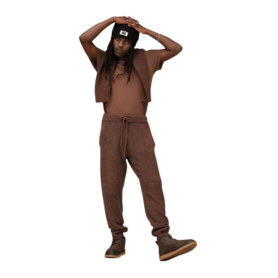 Modelo vistiendo las botas UGG Neumel Moc Nubuck color Dusted Cocoa combinadas con pantalón marrón y gorro negro.