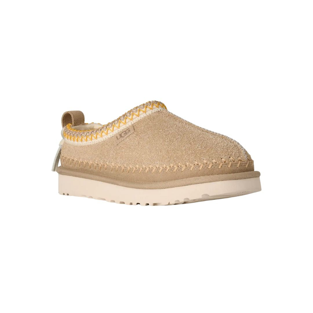 Vista en ángulo de las UGG Tasman Biarritz color mustard seed con empeine de ante y suela EVA ligera.
