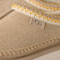 Primer plano del ribete trenzado UGGbraid en poliéster reciclado de las UGG Tasman Biarritz color mustard seed.