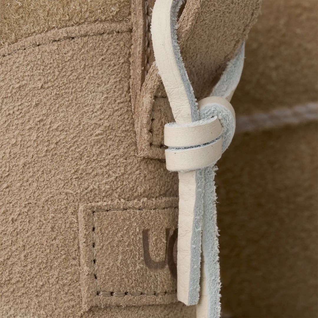 Detalle del nudo de piel trasero de las botas UGG Ultra Mini Biarritz color Mustard Seed.