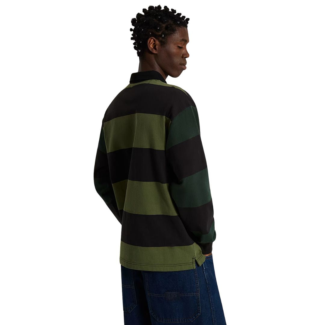 Vista trasera completa del polo de rugby Vans Ward de punto a rayas anchas verde y negro, combinado con vaqueros anchos, mostrando la caída holgada del punto en la espalda.