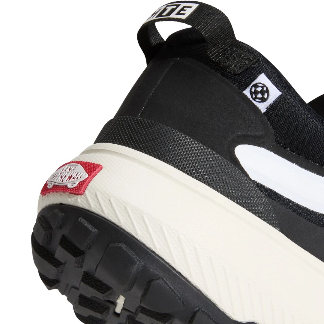Primer plano lateral del talón de la zapatilla Vans MTE Crosspath en negro y blanco, con el parche rojo Vans Off The Wall sobre la voluminosa suela clara.