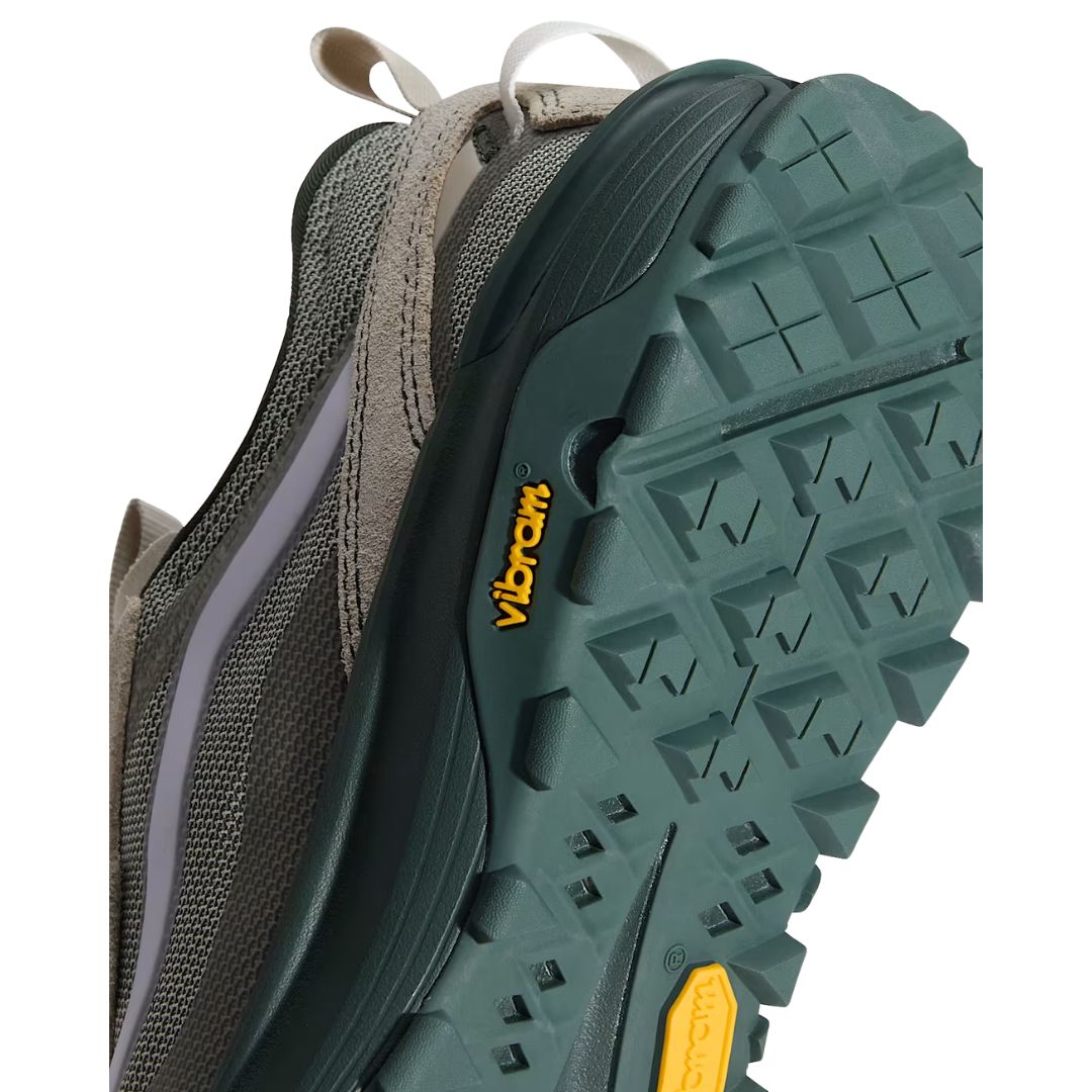 Primer plano de la suela de la zapatilla Vans Crosspath XC en verde salvia y oatmeal, con la etiqueta amarilla Vibram y el dibujo de tacos ranurado en verde oscuro.