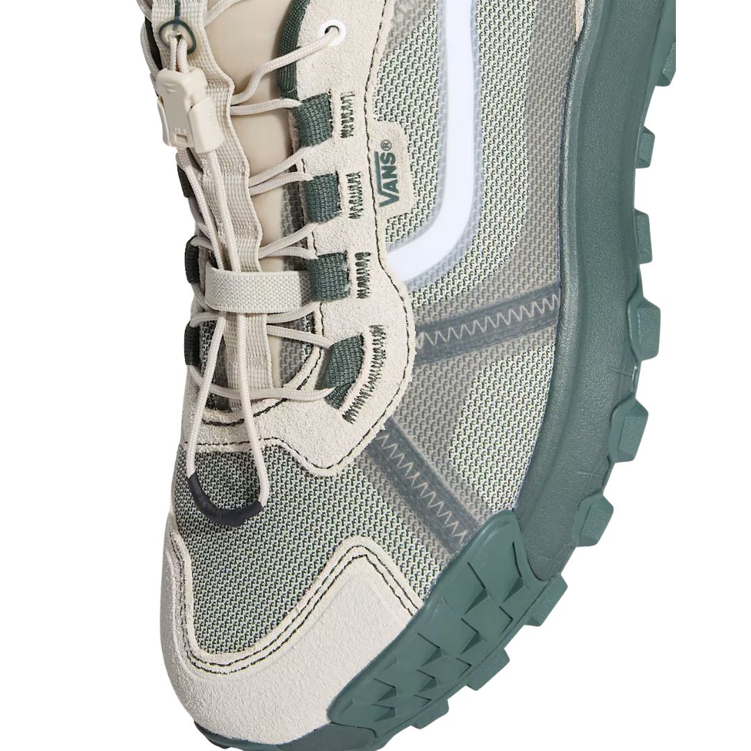 Primer plano frontal de la zapatilla Vans Crosspath XC en verde salvia y oatmeal, mostrando el clip de atado rápido, el logotipo Vans y la Sidestripe blanca sobre la malla.