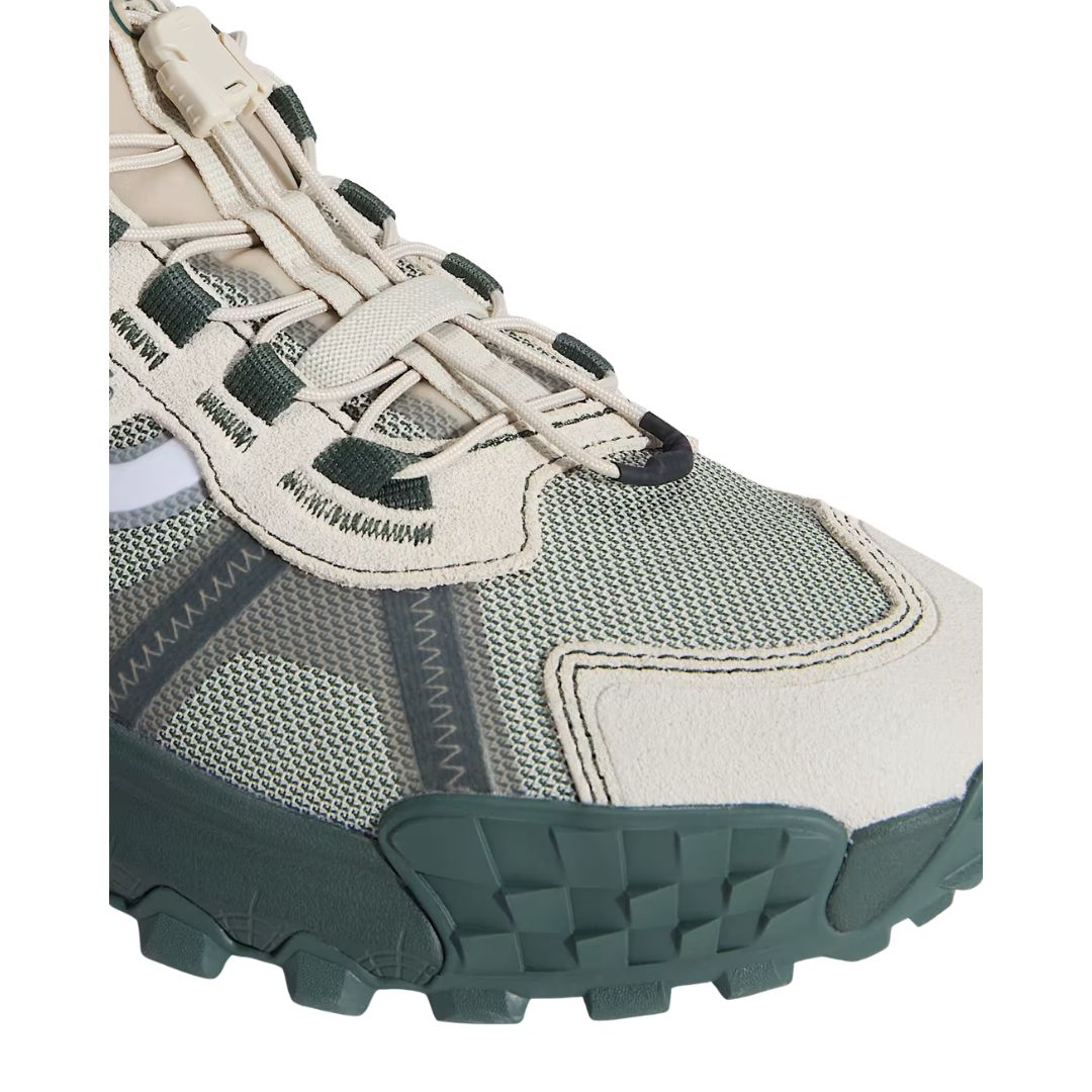 Primer plano de los cordones y el clip Speedlace de la zapatilla Vans Crosspath XC en verde salvia y oatmeal, con los pasadores verde oscuro sobre la malla técnica.