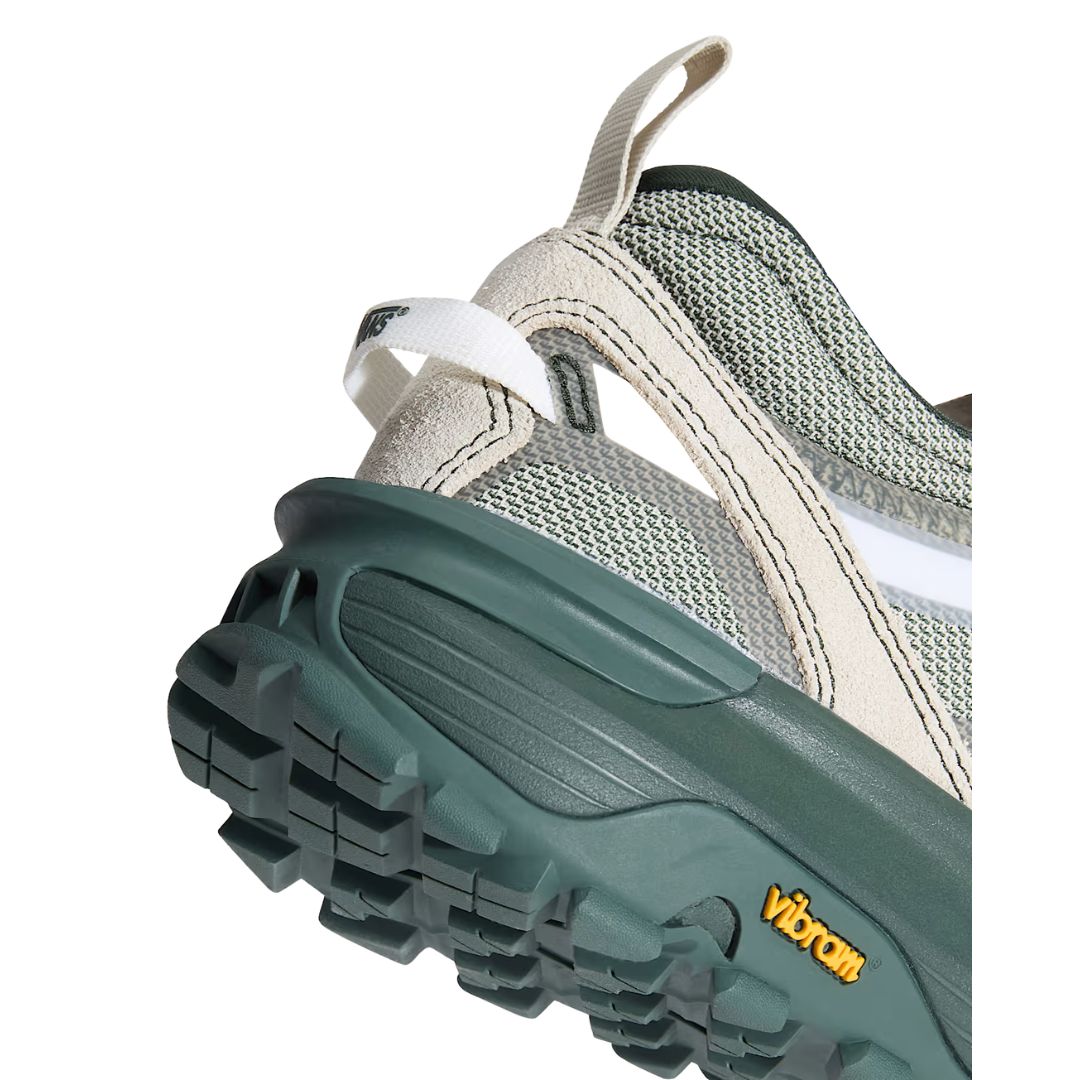 Primer plano del talón de la zapatilla Vans Crosspath XC en verde salvia y oatmeal, con la trabilla trasera color hueso y la voluminosa suela verde con etiqueta amarilla Vibram.