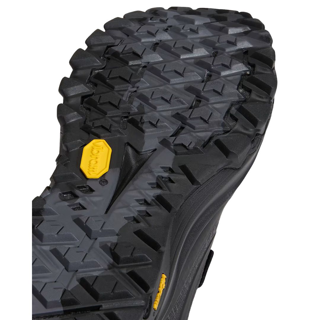 Primer plano de la suela Vibram XS Trek Evo de la zapatilla Vans Crosspath XC Gore-Tex en negro, mostrando el dibujo de tacos ranurado y la etiqueta amarilla Vibram.