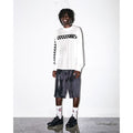 Hombre con camiseta Vans blanca de manga larga y logo a cuadros, pantalón corto oscuro y calcetines Vans, calzando las zapatillas Vans Crosspath XC Gore-Tex en negro bajo un efecto de agua salpicando.