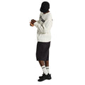 Hombre con sudadera Vans blanca de logo a cuadros y pantalón corto negro, calzando las zapatillas Vans Crosspath XC Gore-Tex en negro, vista lateral completa con las manos entrelazadas.