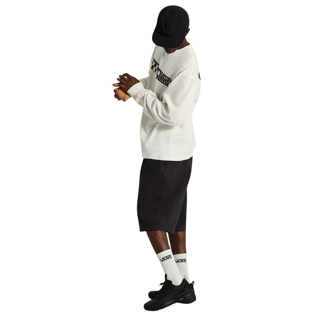 Hombre con sudadera Vans blanca de logo a cuadros y pantalón corto negro, calzando las zapatillas Vans Crosspath XC Gore-Tex en negro, vista lateral completa con las manos entrelazadas.
