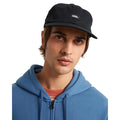 Modelo con Vans Jockey negra puesta, gorra de perfil bajo con visera plana y parche Vans frontal.