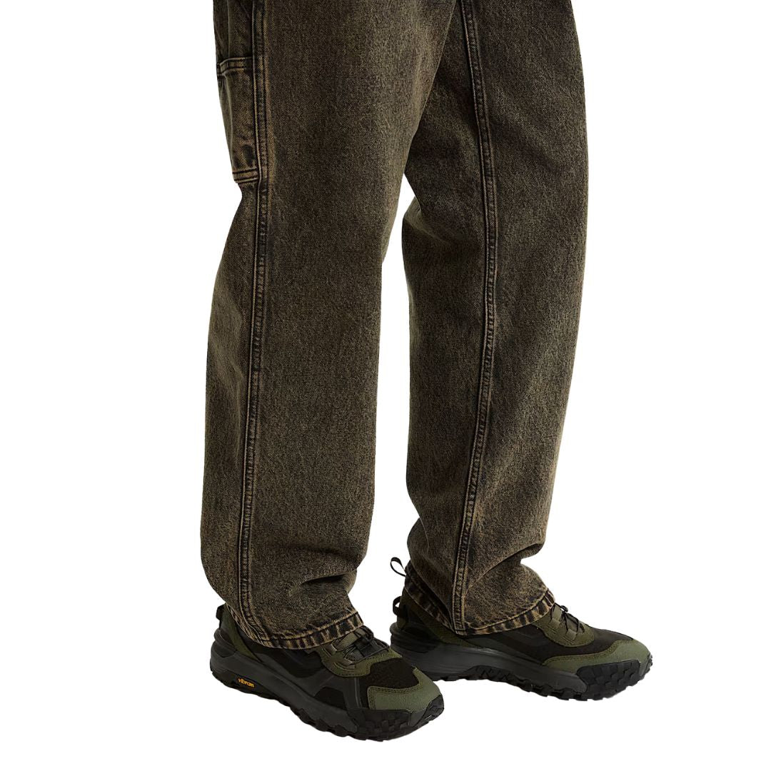 Vista lateral en uso de las Vans MTE Crosspath XC color verde oscuro combinadas con vaqueros.