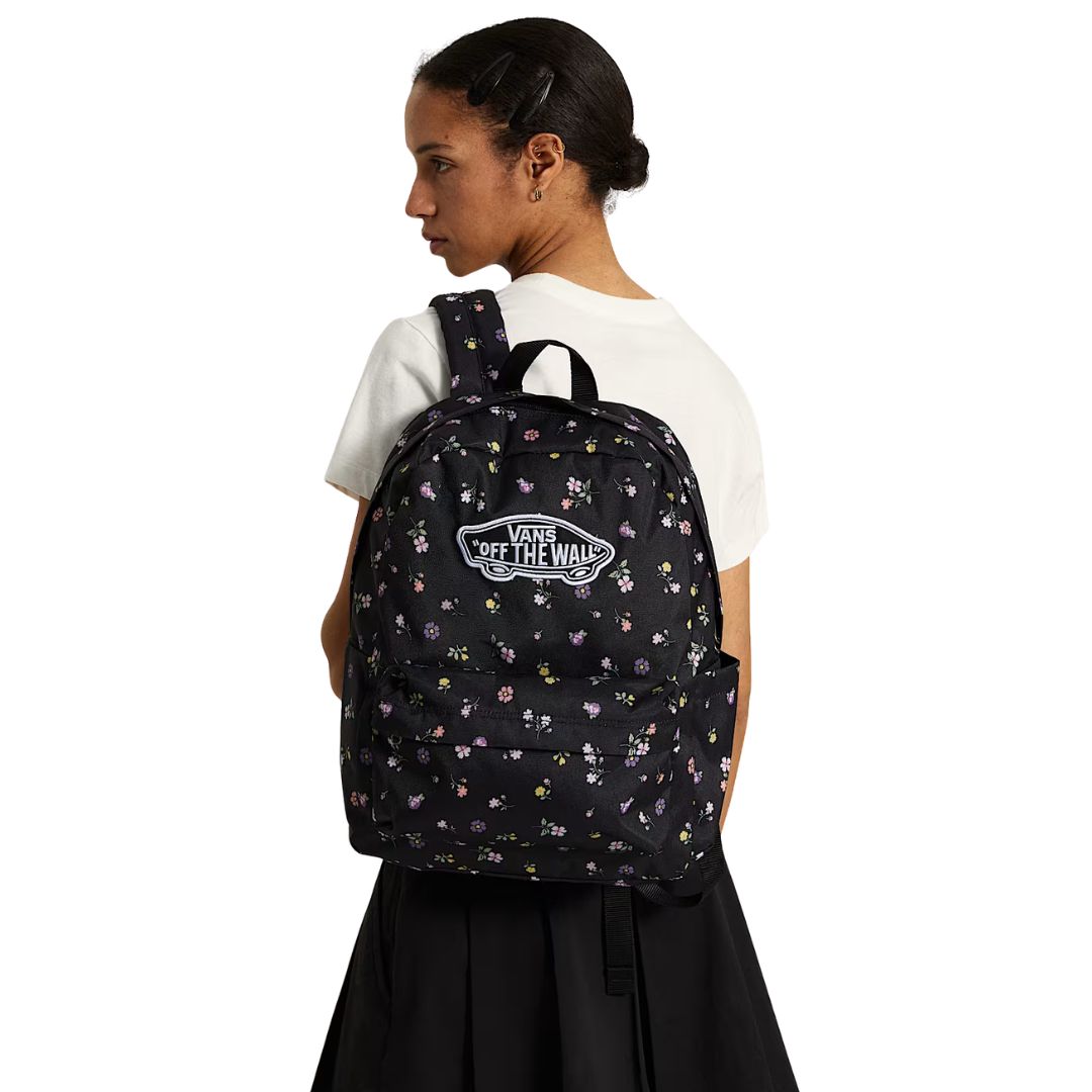 Mochila Vans Old Skool Classic en color black floral, foto de modelo llevándola a la espalda, mostrando el ajuste de las correas y el parche VANS en uso real.
