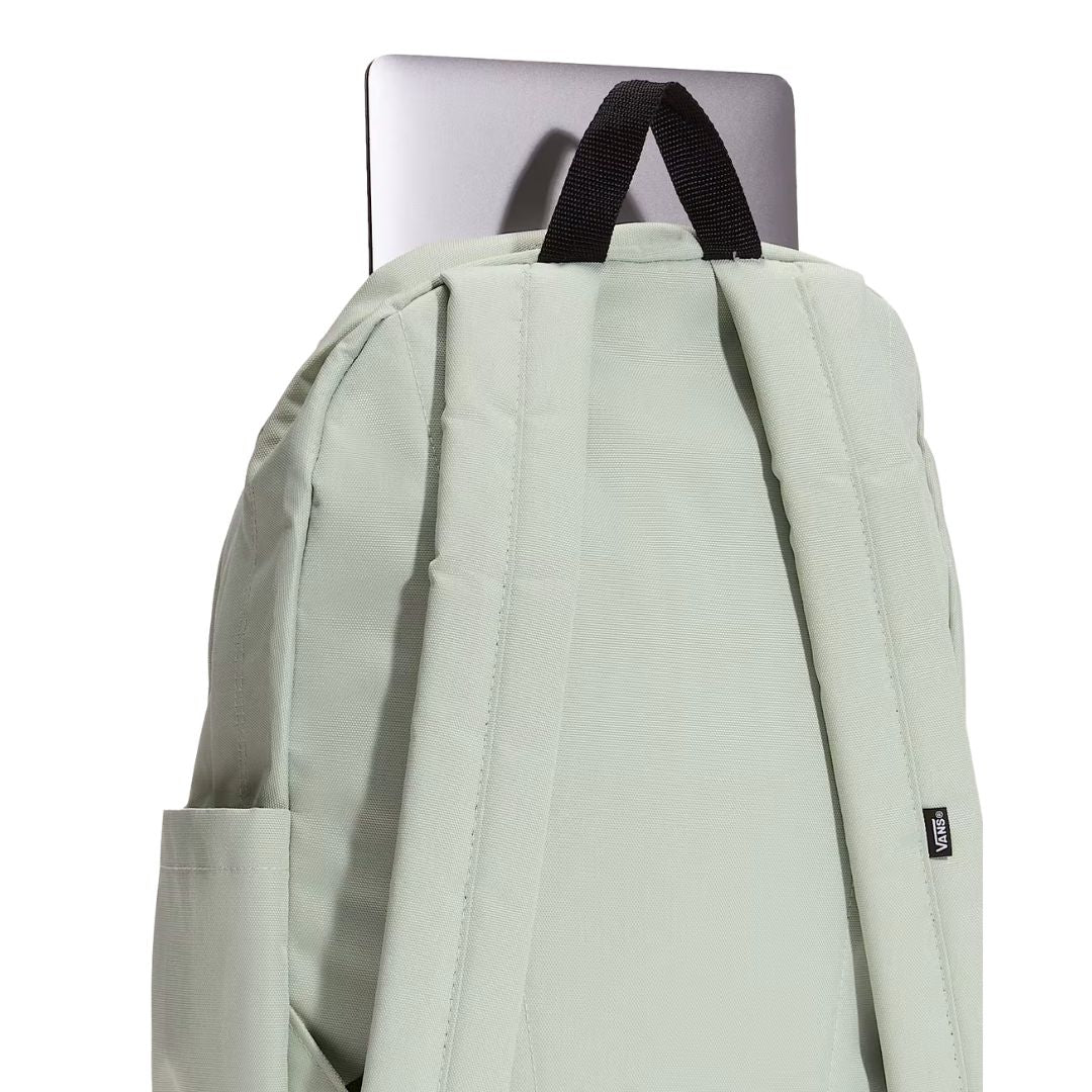 Mochila Vans Old Skool Classic en color dusty green, detalle del asa superior junto a un portátil, mostrando la resistencia del agarre para transportarla.