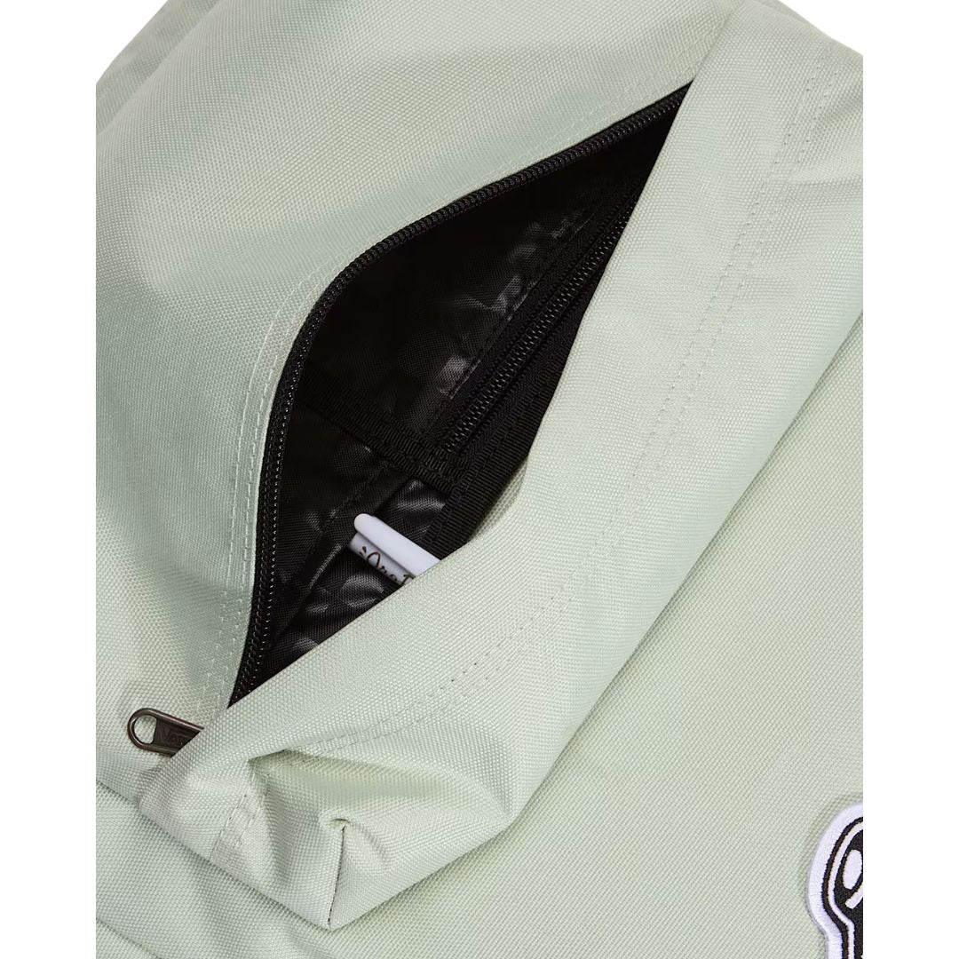 Mochila Vans Old Skool Classic en color dusty green, detalle del bolsillo frontal abierto con unos auriculares, mostrando la cremallera y el parche VANS.