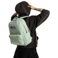 Mochila Vans Old Skool Classic en color dusty green, foto de modelo llevándola a la espalda con capucha puesta, mostrando el ajuste de las correas en uso real.