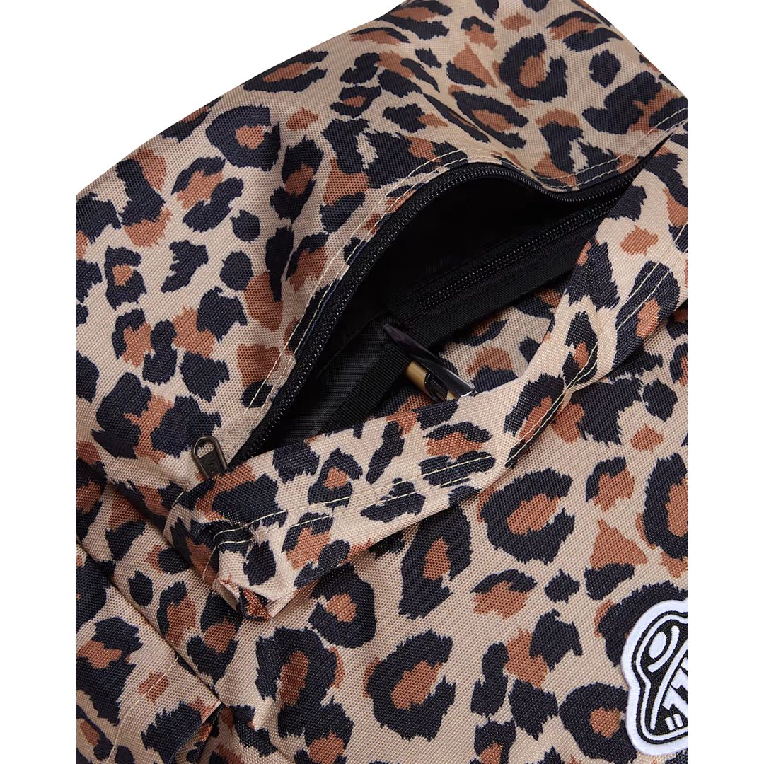 Mochila Vans Old Skool Classic en color incense (estampado leopardo), detalle del bolsillo frontal abierto con un bolígrafo, mostrando la cremallera y el parche VANS.