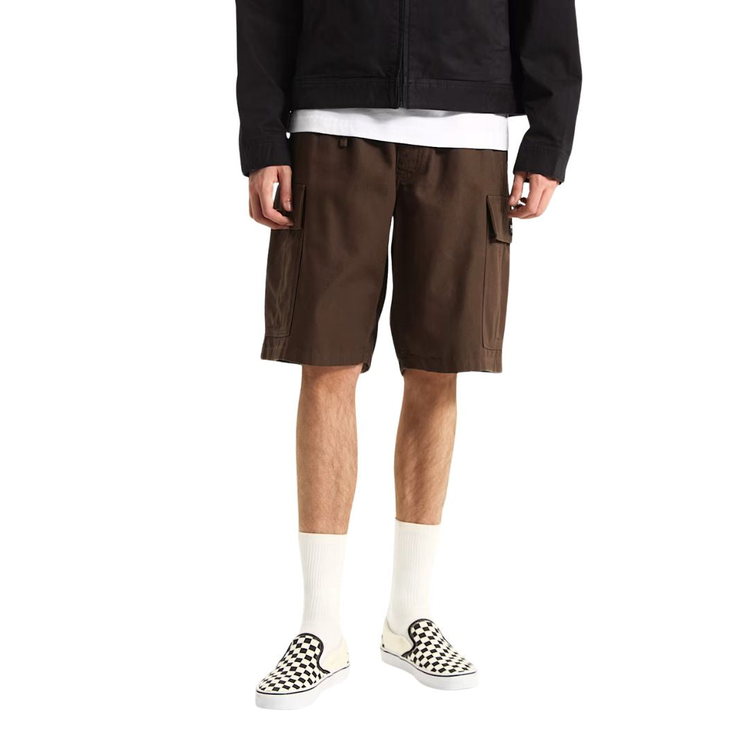 Modelo con Vans Range Cargo Shorts marrón de corte loose fit, bermudas cargo 100% algodón con bolsillos laterales con solapa, cintura elástica con cordón y bolsillos delanteros inclinados.