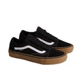 Par de zapatillas Vans Skate Old Skool en color negro con suela gum, vista en ángulo mostrando la icónica franja lateral blanca sobre lona y ante, silueta skate clásica de Vans.