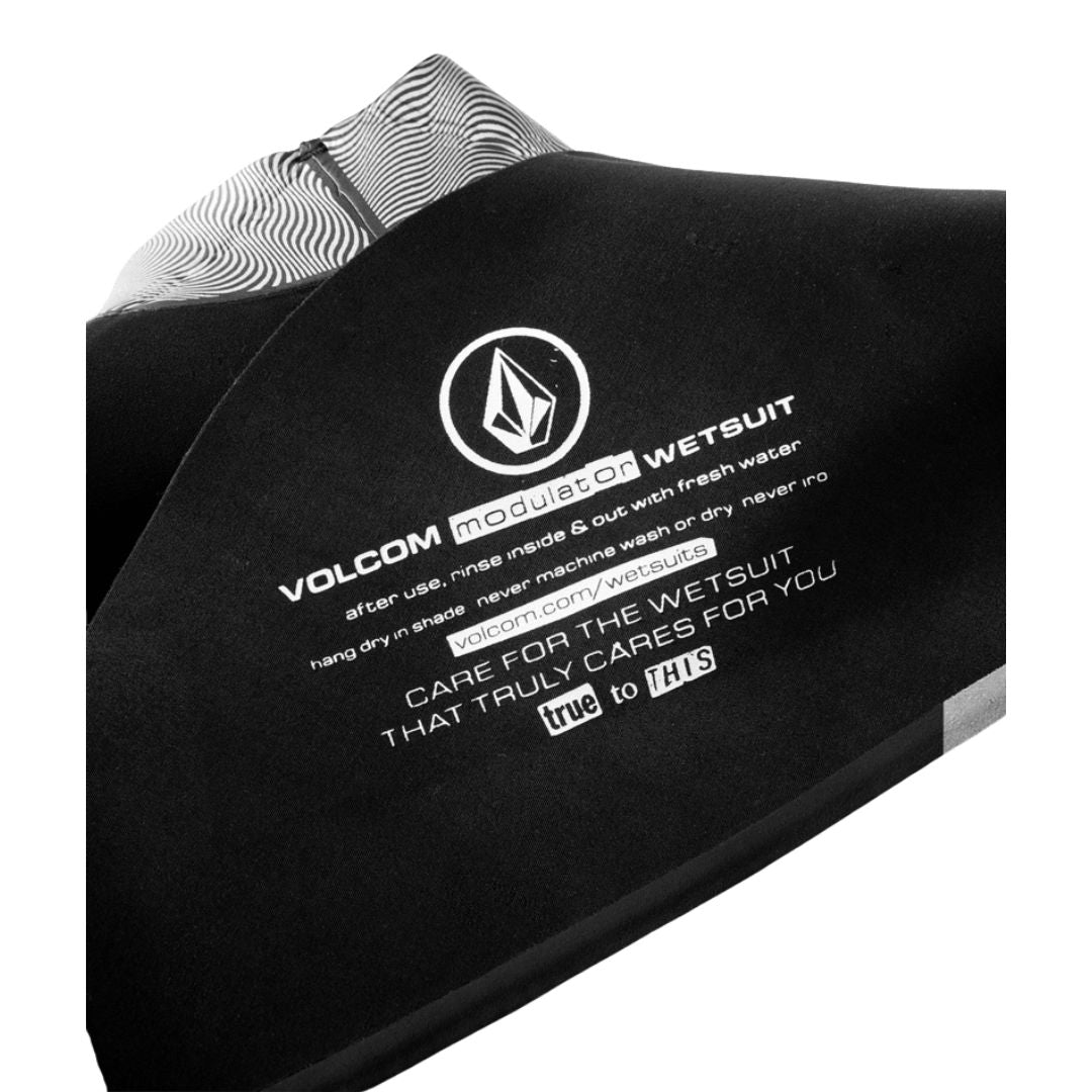 Detalle interior espalda traje neopreno Volcom 2/2mm negro con instrucciones de cuidado.