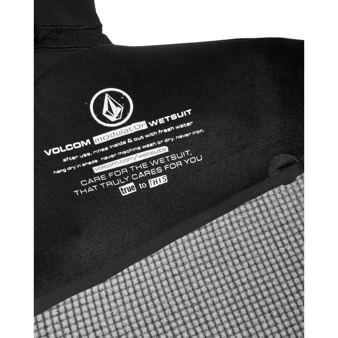 Detalle interior con instrucciones de cuidado del traje de neopreno Volcom Modulator 5/4/3 mm negro con capucha y cremallera en el pecho.