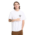 Modelo con la camiseta Volcom Bad Luck SST en color blanco, vista frontal cercana con los brazos relajados, mostrando el escudo Volcom EST. 91 en el pecho.