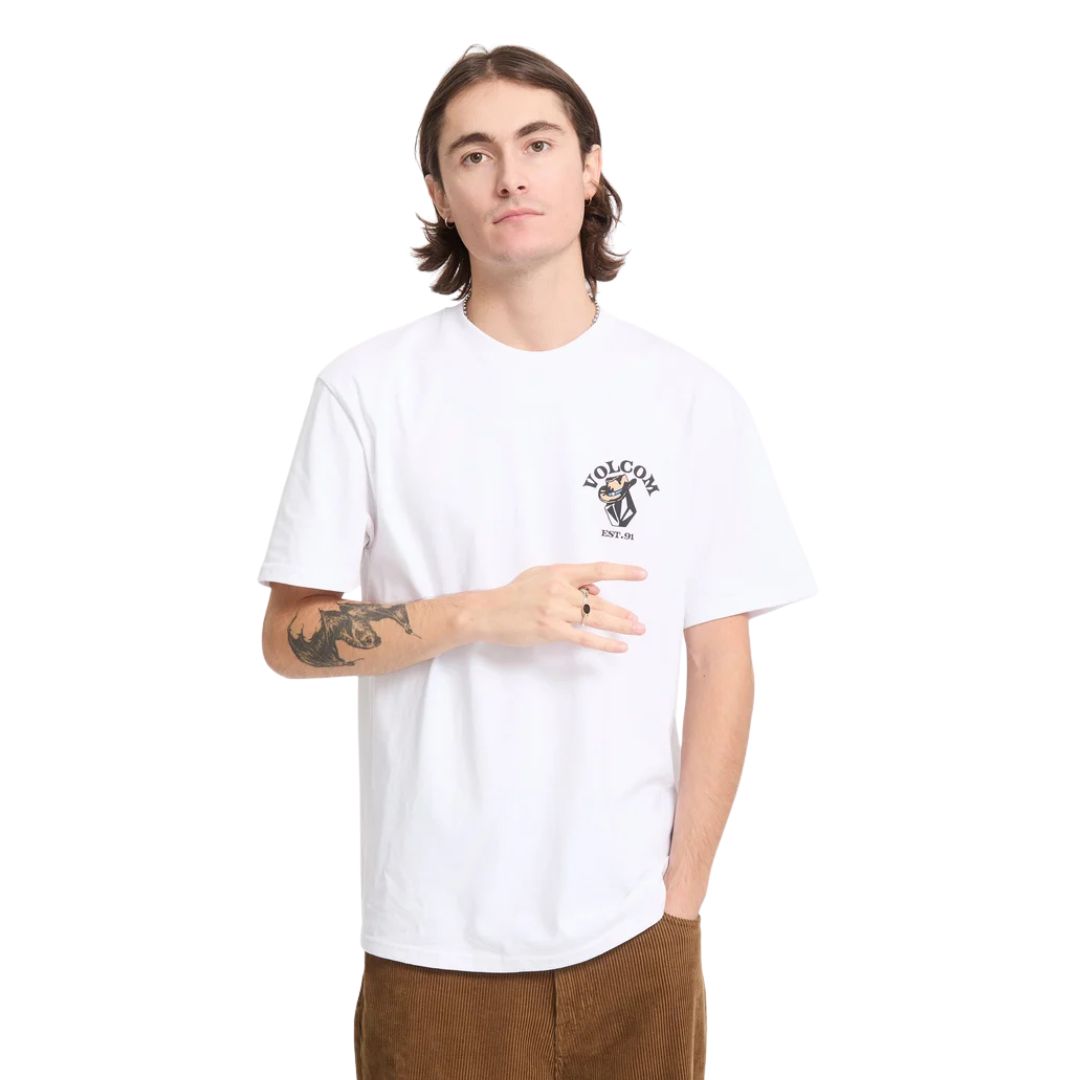 Modelo con la camiseta Volcom Bad Luck SST en color blanco, vista frontal cercana con los brazos relajados, mostrando el escudo Volcom EST. 91 en el pecho.