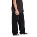 Pantalón vaquero ancho Volcom Billow Denim en negro, vista lateral de perfil que muestra el volumen del corte loose y el largo total sobre zapatillas Converse.