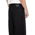 Detalle trasero del pantalón vaquero Volcom Billow Denim negro con la etiqueta Volcom y la etiqueta informativa del proceso de lavado sostenible Water Aware.