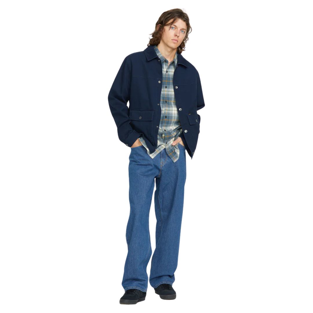 Modelo masculino vistiendo Volcom Billow Denim bold blue, look completo con chaqueta azul marino y camisa de cuadros.