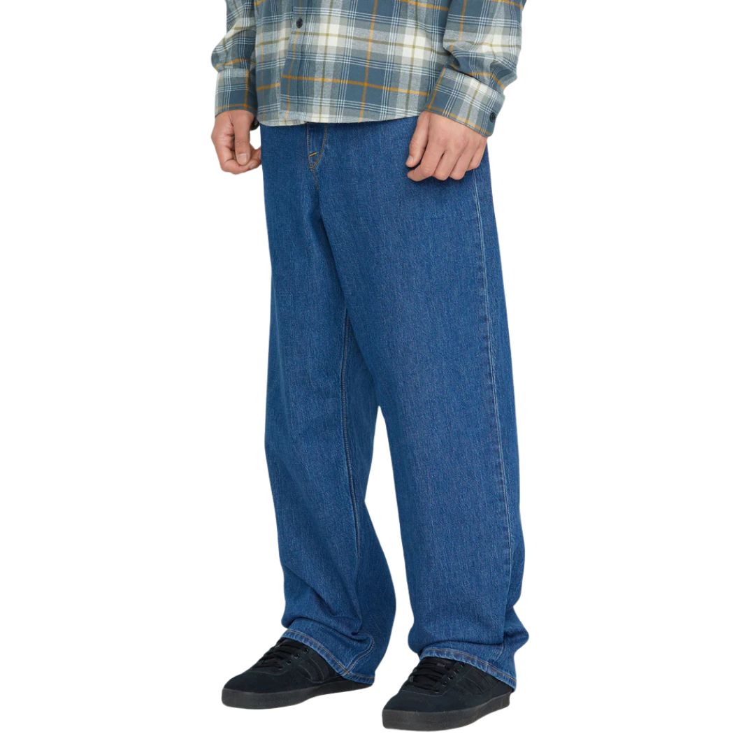 Pantalón vaquero Volcom Billow Denim bold blue para hombre, corte amplio, combinación con camisa de cuadros y zapatillas negras.