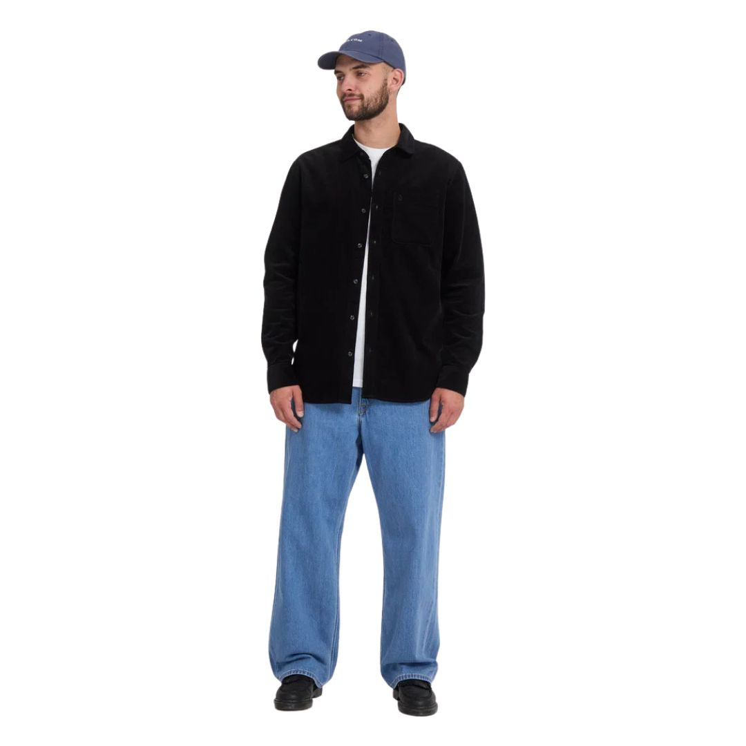 Vaquero Volcom Billow Denim en azul Cali Blue sobre modelo con gorra y camisa negra, vista frontal que muestra el volumen del corte loose desde la cadera hasta el bajo.