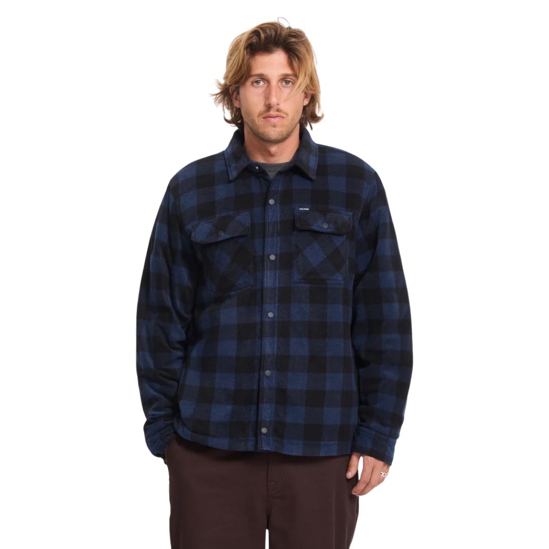 Hombre con sobrecamisa Volcom Bowered II en color azul marino a cuadros completamente abrochada, vista frontal de medio cuerpo mostrando el cuello simple.
