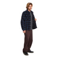 Vista lateral de hombre con sobrecamisa Volcom Bowered II en color azul marino a cuadros, sujetando la prenda abierta y mostrando el forro acolchado interior.