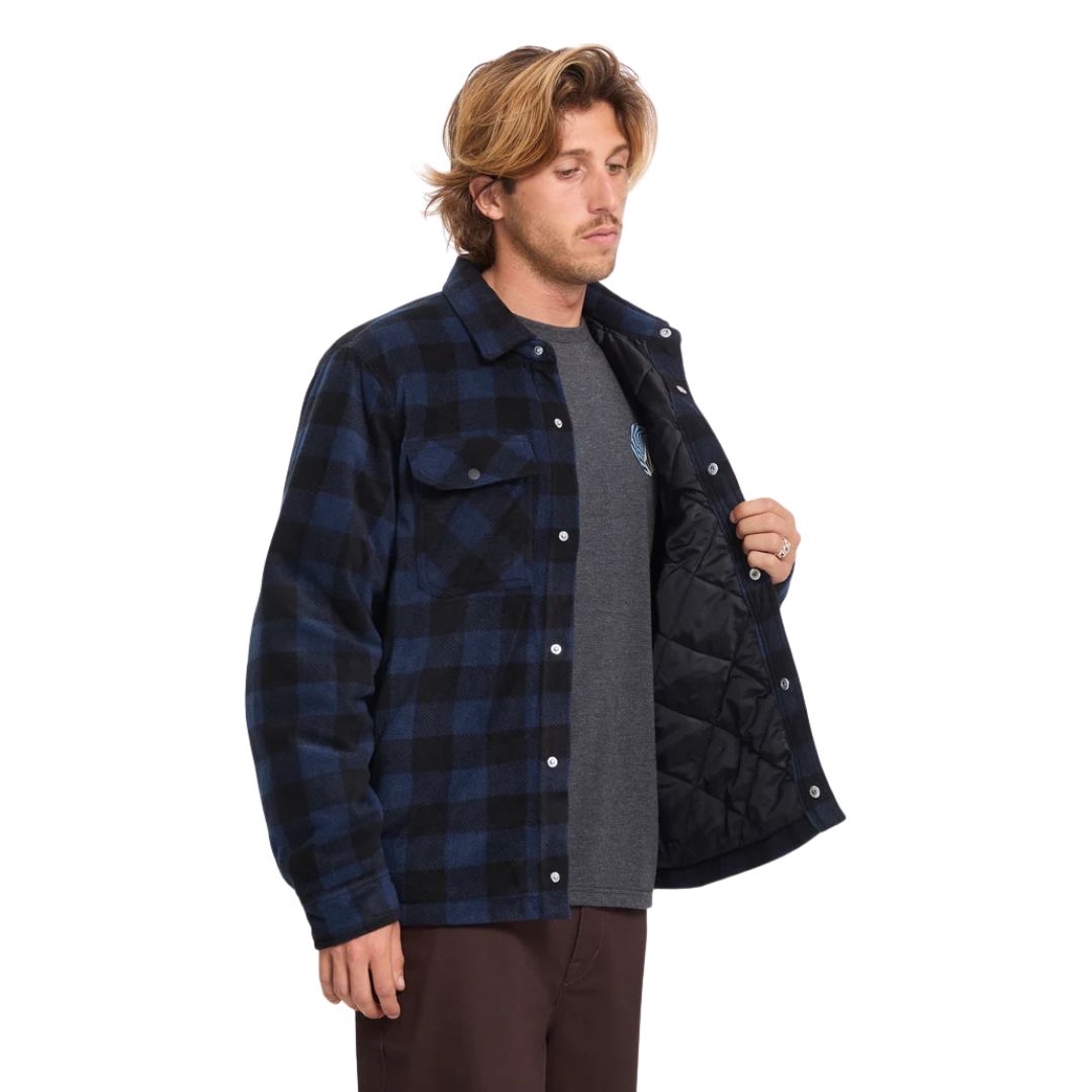 Hombre con sobrecamisa Volcom Bowered II en color azul marino a cuadros abierta, mostrando el forro de tafetán acolchado en el interior de la prenda y el cuello simple.