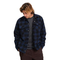 Hombre con sobrecamisa Volcom Bowered II en color azul marino a cuadros abierta sobre camiseta gris, mostrando el cuello simple y el corte boxy de la prenda.
