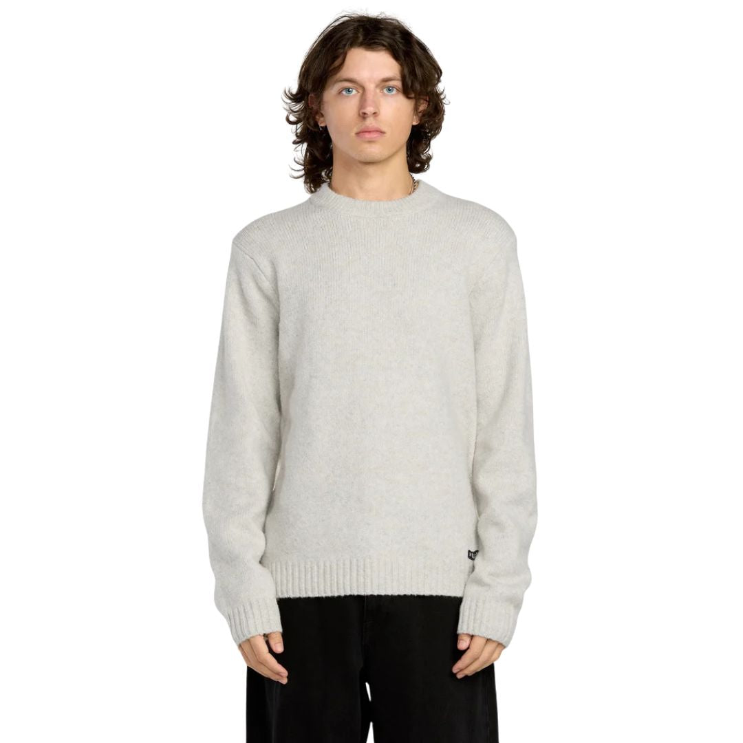 Hombre con jersey Volcom Edmonder II en color blanco roto, vista frontal de medio cuerpo, mostrando el cuello redondo y la textura jaspeada del punto grueso.