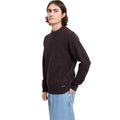 Vista lateral de hombre con jersey Volcom Edmonder II en color pasa, con la mano en el bolsillo del pantalón y la etiqueta Volcom visible junto al bajo.