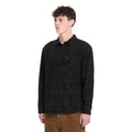 Hombre con camisa Volcom Hunkstone LS en color cacao a cuadros, vista de tres cuartos mostrando los botones delanteros y el estampado de cuadros completo.