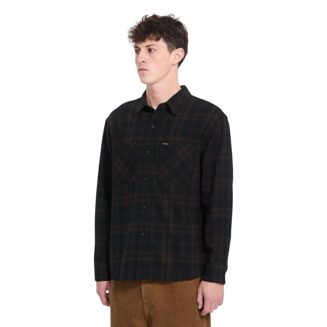Hombre con camisa Volcom Hunkstone LS en color cacao a cuadros, vista de tres cuartos mostrando los botones delanteros y el estampado de cuadros completo.