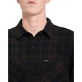 Detalle del cuello y el bolsillo del pecho de la camisa Volcom Hunkstone LS en color cacao a cuadros, con la etiqueta Volcom cosida bien visible en el pecho.