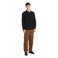 Hombre con camisa Volcom Hunkstone LS en color cacao a cuadros de cuerpo entero, combinada con pantalón de pana, luciendo el corte boxy de la prenda completa.