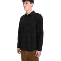 Hombre con camisa Volcom Hunkstone LS en color cacao a cuadros, en ángulo de tres cuartos, mostrando el doble bolsillo en el pecho y el cuello simple de la prenda.