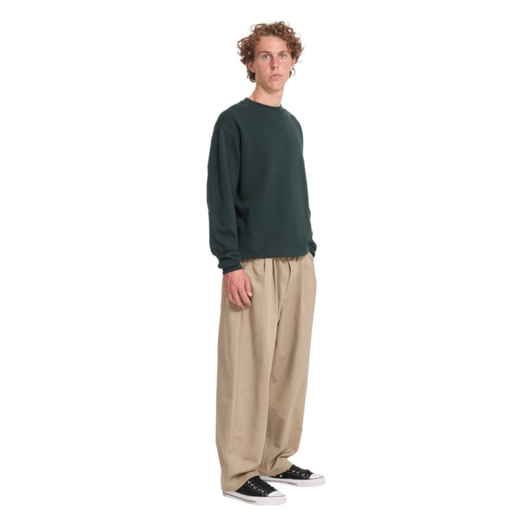 Sudadera Volcom Single Stone Crew en color Scarab, vista lateral de cuerpo entero combinada con pantalón beige y zapatillas Converse, mostrando el corte clásico.