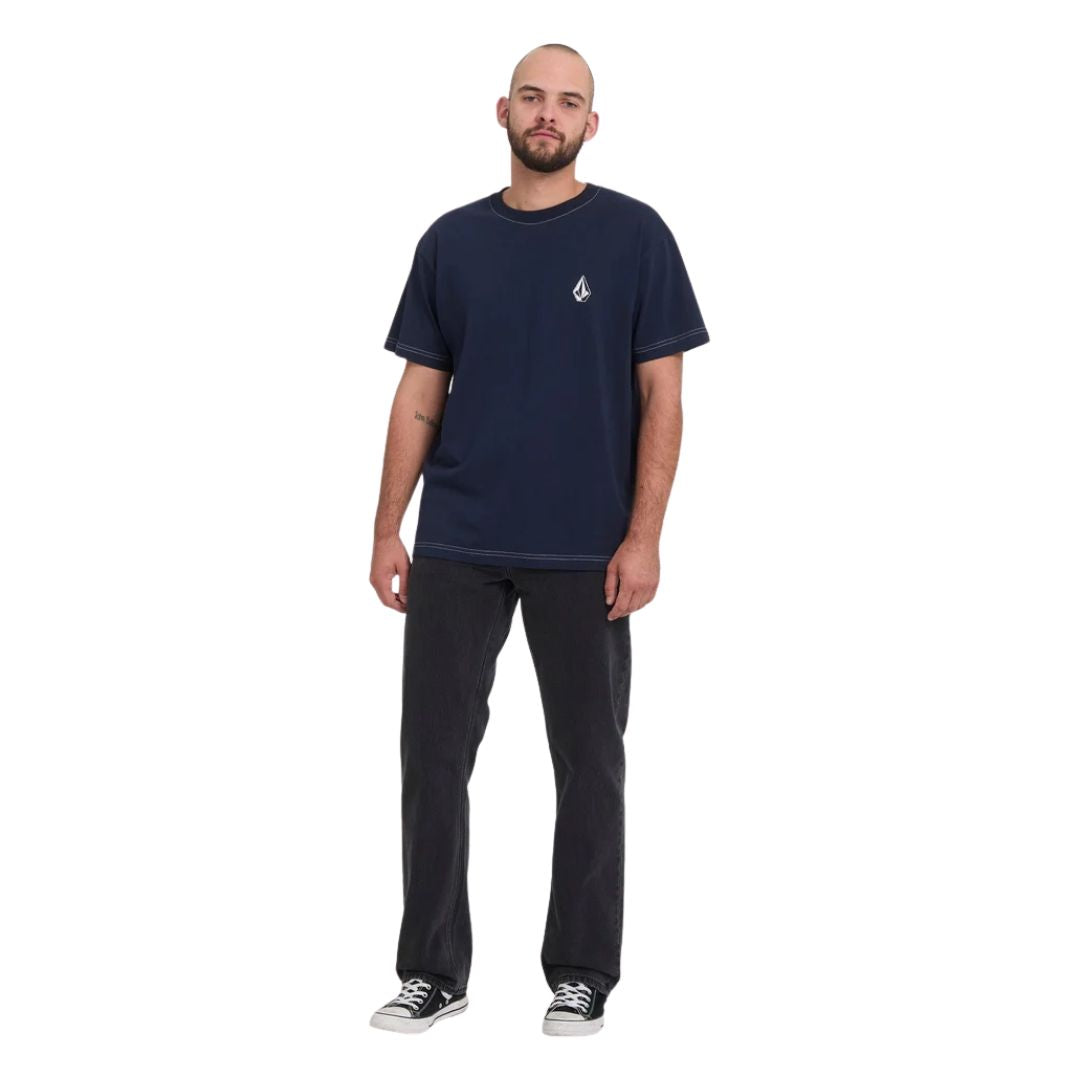 	Pantalón vaquero Volcom Kinkade Denim en negro lavado, vista frontal completa sobre modelo con camiseta azul marino, mostrando el corte normal y la pierna recta.