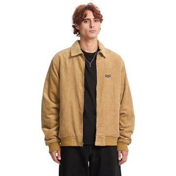 Hombre con chaqueta Volcom Kurtis en color armiño, vista frontal de cuerpo entero con la cremallera bajada y el logo Volcom bordado en el pecho visible.