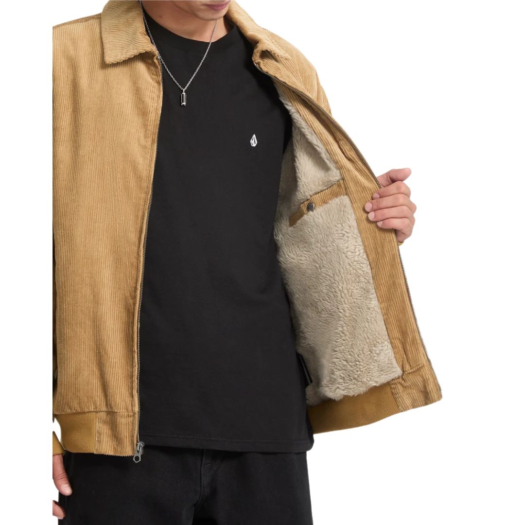 Detalle de hombre abriendo la chaqueta Volcom Kurtis en color armiño, mostrando el forro interior de piel sintética y el bolsillo interno de la prenda.