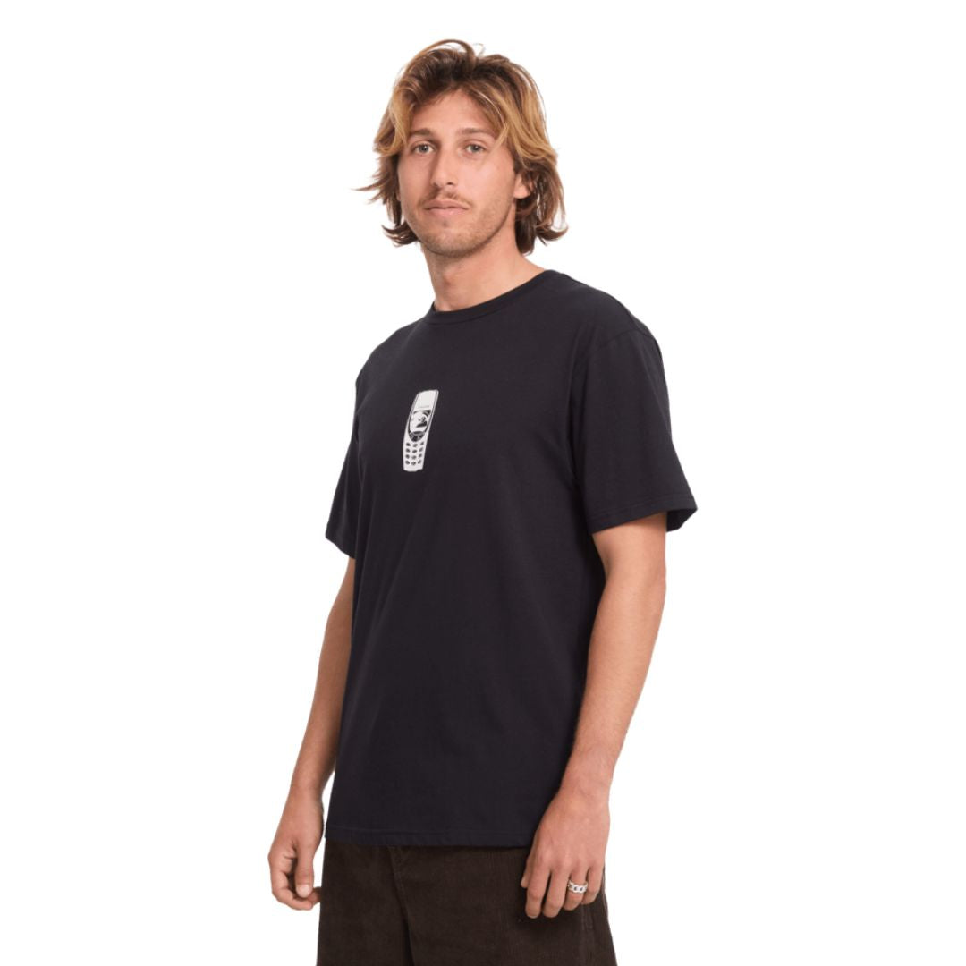 Modelo con la camiseta Volcom Last Call BSC SST en color negro, vista de perfil de tres cuartos mostrando el pequeño estampado del teléfono en el pecho.