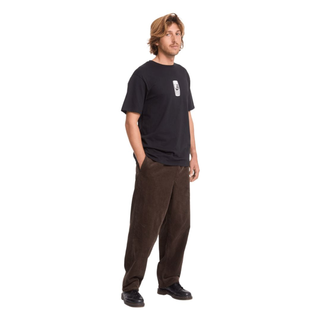 Modelo con la camiseta Volcom Last Call BSC SST en color negro, vista frontal con la mano en el bolsillo, mostrando el estampado del teléfono retro en el pecho.